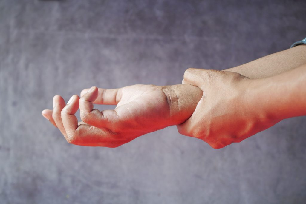Close-up of hands, one grasping the other, symbolizing pain or discomfort.