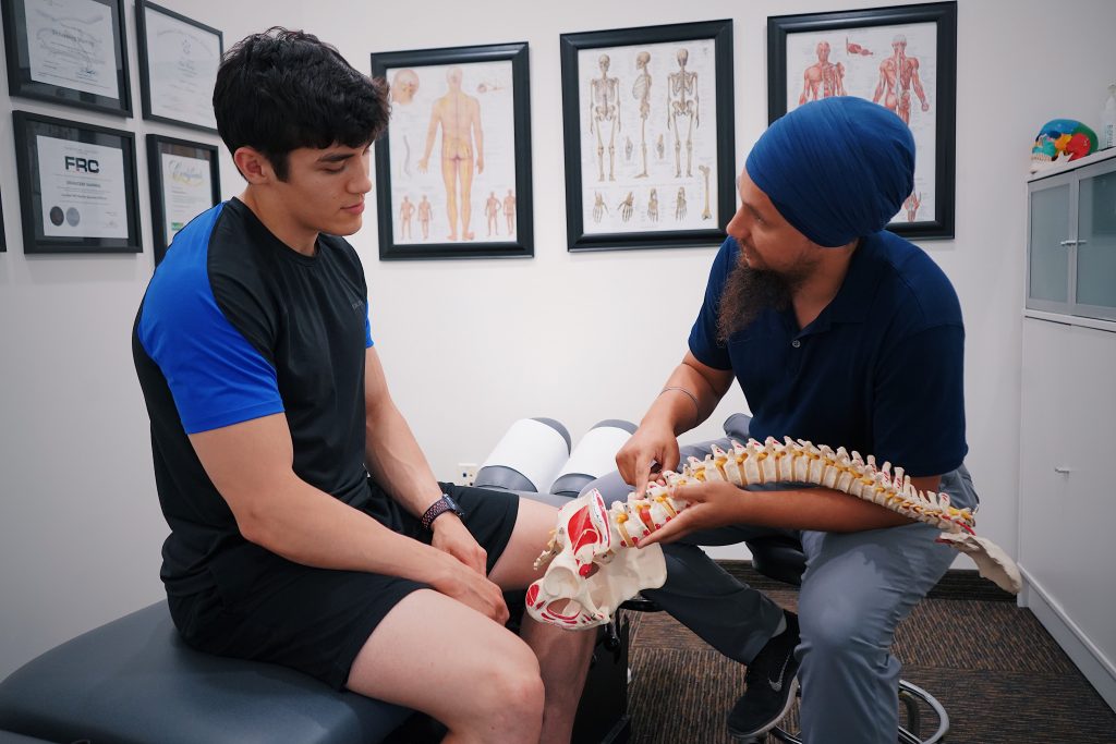 Spinal Trauma A doctor explains spinal issues to a patient using a spine model during a medical consultation.