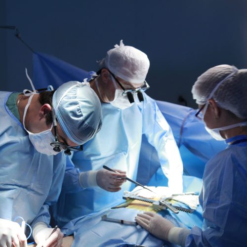 Team of surgeons meticulously performing surgery in a sterile operating room, highlighting expert medical care.